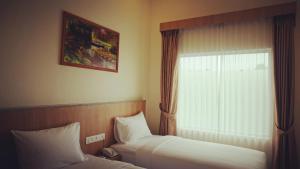 丹戎槟榔Bintan Lumba Lumba Inn Hotel的有两张床和一扇窗户的酒店房间