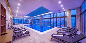 a pool in a building with chairs and windows at The Green Park Sivas in Sivas