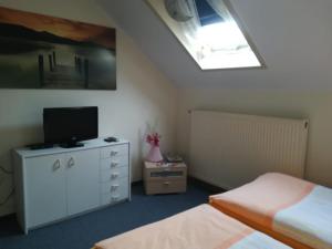 a bedroom with two beds and a television on a dresser at Kyffhäuserhotel "Goldene Aue" in Wallhausen