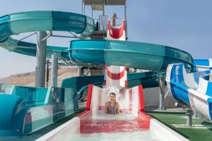 un niño montando un tobogán de agua en una montaña rusa en Leonardo Club Hotel Dead Sea - All Inclusive, en Ein Bokek