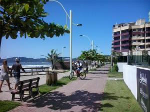 a person riding a bike on a sidewalk next to the beach at Casa na praia in Porto Belo