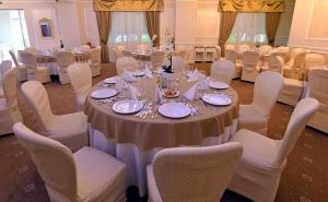 een eetkamer met een tafel en stoelen met borden en bestek bij Vip Motel Restaurant in Haţeg