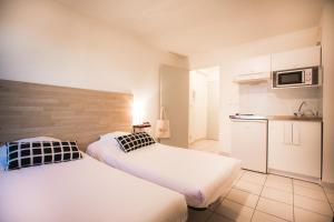 twee bedden in een kleine kamer met een keuken bij City Résidence Avignon (5 Epi) in Avignon
