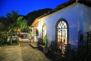 a white building with two windows and a palm tree at Jardim da Marambaia in Barra de Guaratiba