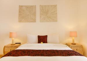 a bedroom with a white bed with two lamps at Villa Del Mar Canggu in Canggu