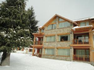 a house in the snow with a tree at Unquehue Apartamentos Dormis in Villa La Angostura
