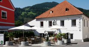 un edificio con mesas y sombrillas delante en Gasthof Eckberg, en Unzmarkt