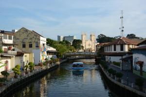 a small boat in a canal in a city at 1511 Guest House in Malacca