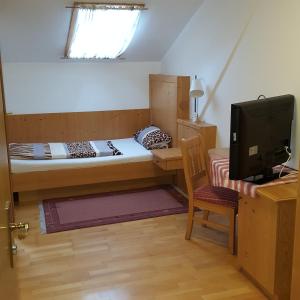 a small bedroom with a bed and a desk with a computer at Lenggrieser Hof in Lenggries