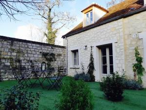 a stone house with a table in the yard at L'ancien Presbytère in Coye-la-Forêt