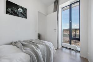 a white bedroom with a bed and a large window at BJØRVIKA APARTMENTS, Opera Area, Oslo city center in Oslo