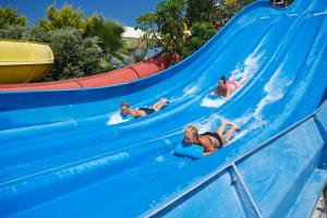 a group of people riding a water slide at a water park at Louis Phaethon Beach in Paphos