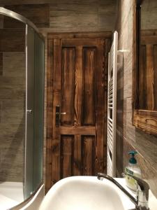 a bathroom with a sink and a wooden door at Privat 66 in Liptovský Trnovec