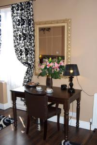 a table with a vase of flowers and a mirror at Villaggio in Warrington