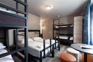 a room with three bunk beds and a table at a&o Warszawa Wola in Warsaw