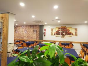 a conference room with tables and chairs and plants at Hostal Restaurante El Abuelo in Trobajo del Camino