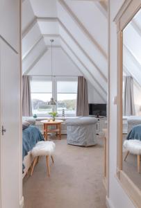 a bedroom with white ceilings and a room with a table at Weisse Düne - West in Wenningstedt