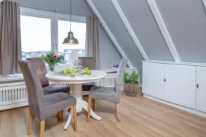 a dining room with a white table and chairs at Weisse Düne - Ost in Wenningstedt