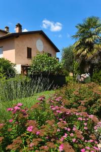un jardin avec des fleurs roses en face d'une maison dans l'établissement Il Giardino Segreto, à Iseo