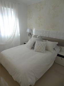 Cama blanca con almohadas blancas y ventana en Infostays María Zambrano - Free Parking en Málaga
