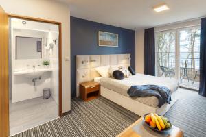 ein Schlafzimmer mit Bett und ein Badezimmer mit Waschbecken in der Unterkunft Villa Dune in Sarbinowo