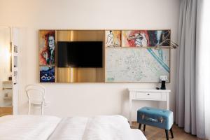a bedroom with a bed, desk, television and a painting on the wall at Hotel Schani Salon in Vienna