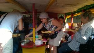 a woman is holding a plate of food in a trailer at Nature Camp Bhitarkanika Retreat in Righāgarh
