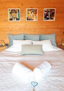 a large white bed with pictures on the wall at צימרגולה in ‘En Yahav