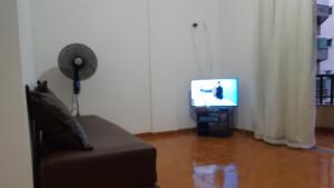 sala de estar con sofá y TV en Apartamento na Prainha (1 quadra), en Arraial do Cabo