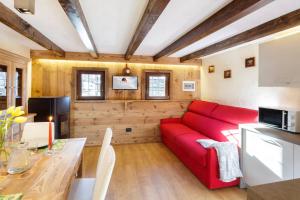 a living room with a red couch and a table at HelloChalet - Chalet Grené typical house with garden - 1km cabelcar in Valtournenche