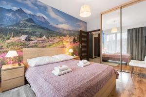 a bedroom with a large bed with towels on it at Apartamenty Oaza Superior Zakopane in Zakopane
