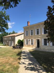 un grand bâtiment blanc avec deux bancs devant lui dans l'établissement Domaine Cazenave, à Budos