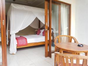 a bedroom with a canopy bed and a table at Raka House Accommodation in Ubud