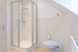 a white bathroom with a shower and a toilet at Weisse Düne - West in Wenningstedt +8 photos