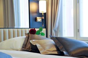 ein Bett mit Kissen und eine Rose darüber in der Unterkunft Hotel Red & Green in Närpiö