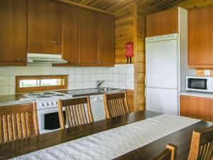 a kitchen with a white refrigerator and wooden cabinets at Holiday Home Yläneuvola silta by Interhome in Neuvola
