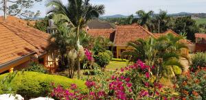 Blick auf ein Haus mit Blumen und Palmen in der Unterkunft Keelan ace villas in Kampala