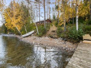 a boat on the shore of a river with a house at Holiday Home Aamuntorkku by Interhome in Vuoriniemi +17 photos