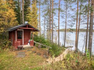 a small cabin in the woods next to a lake at Holiday Home Aamuntorkku by Interhome in Vuoriniemi