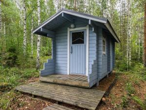a blue outhouse with a wooden deck in the woods at Holiday Home Kuutti by Interhome in Vuoriniemi
