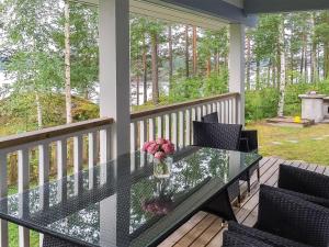 a glass table with a vase of flowers on a porch at Holiday Home Nestori by Interhome in Vuoriniemi