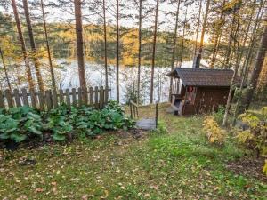 a small house next to a fence next to a body of water at Holiday Home Aurinkorinne by Interhome in Vuoriniemi