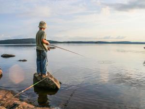 a man standing on a rock fishing on a lake at Holiday Home Ettone by Interhome in Lipinlahti