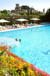 a swimming pool with people in the water and umbrellas at GoOutside Toscana in Sarteano