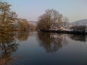 a river with trees and snow on the water at Ferienwohnung am Weyer in Solingen