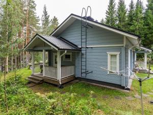 a blue tiny house with a porch in the woods at Holiday Home Kuutti by Interhome in Vuoriniemi