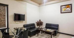 a living room with a couch and a table and a tv at Hotel Simran Pride, Raipur in Raipur
