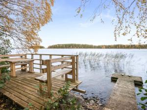 a wooden dock with two benches on a lake at Holiday Home Aamuntorkku by Interhome in Vuoriniemi