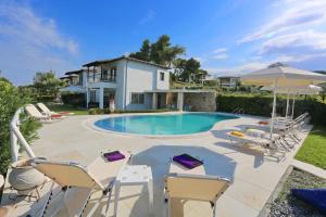 a pool with chairs and umbrellas in front of a house at Nautica Villa in Hanioti