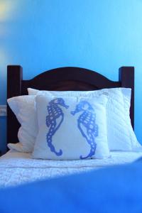 uma cama com uma almofada branca com cavalos-marinhos azuis em Pousada do Cais em Paraty